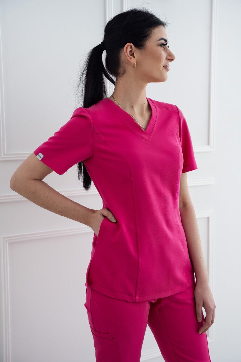 bluzka-medyczna-premium-2-pink-scrabme A woman in pink scrubs standing against a white wall