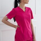A woman in pink scrubs standing against a white wall